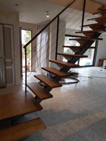 ASMT Design réalise un escalier sur mesure avec limon central et marches frêne blanc, adapté à un espace confiné unique.