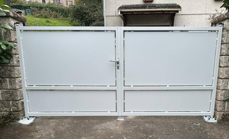 Portail d’entrée battant en acier sur mesure, installé entre piliers béton, offrant sécurité, robustesse et design élégant pour maison individuelle.